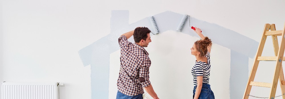 Zwei Personen streichen eine Wand.